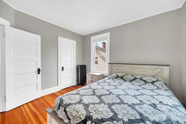 bedroom featuring radiator, ornamental molding, baseboards, and wood finished floors