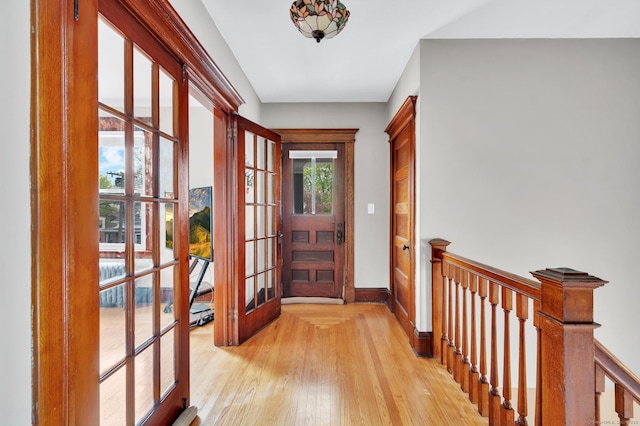 doorway featuring baseboards, french doors, and light wood-style flooring