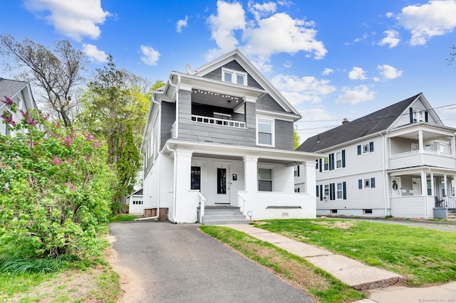 view of front of house with a front lawn, a balcony, and covered porch