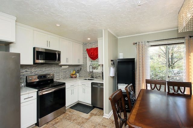 kitchen with a sink, light countertops, stainless steel appliances, and white cabinetry