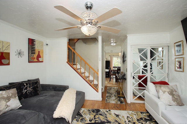 living room featuring crown molding, a ceiling fan, stairs, and hardwood / wood-style floors