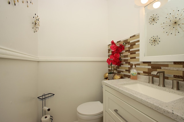 half bath with toilet, tasteful backsplash, and vanity