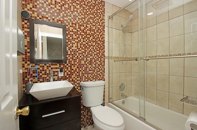 full bath featuring shower / bath combination with glass door, vanity, toilet, and tile walls