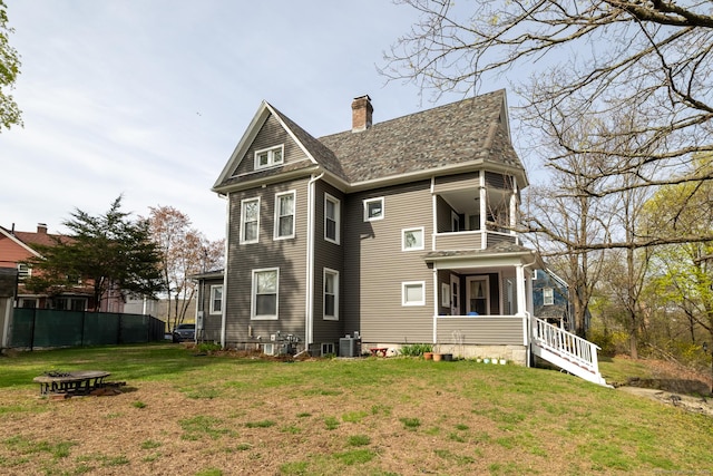 back of house with a chimney, fence, a balcony, and a lawn