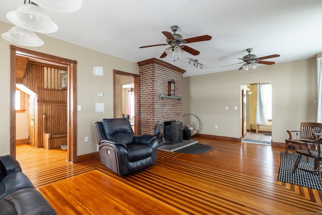 living room with ceiling fan, baseboards, and light wood-style floors