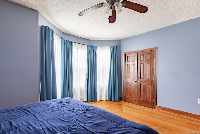 bedroom with a textured ceiling, ceiling fan, wood finished floors, and baseboards