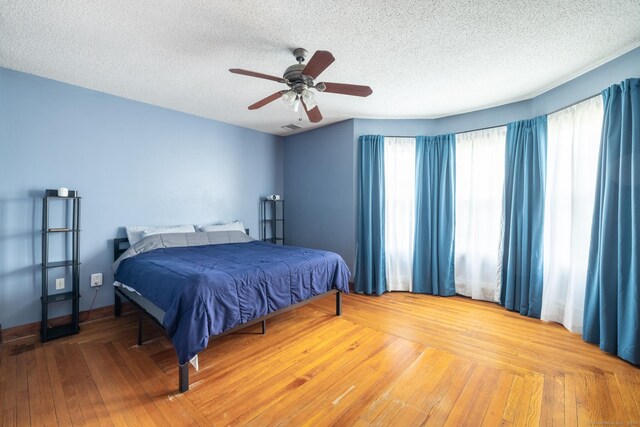 bedroom featuring visible vents, a ceiling fan, a textured ceiling, and wood-type flooring