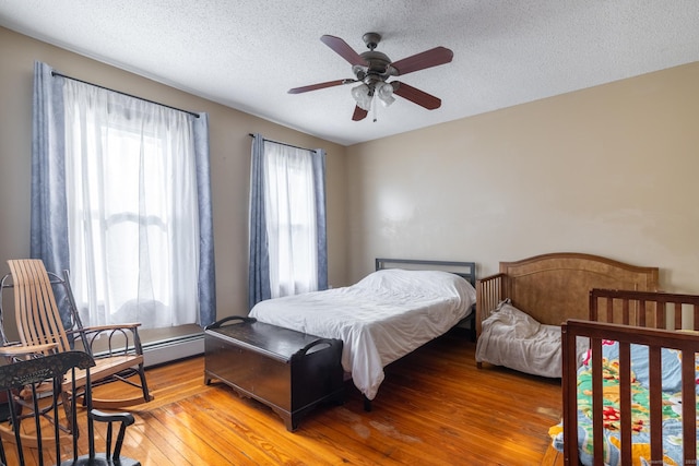 bedroom with a textured ceiling, a ceiling fan, and light wood finished floors