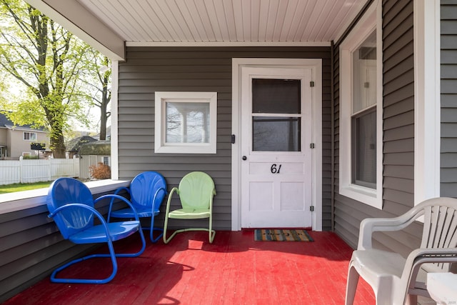 view of exterior entry featuring fence and covered porch
