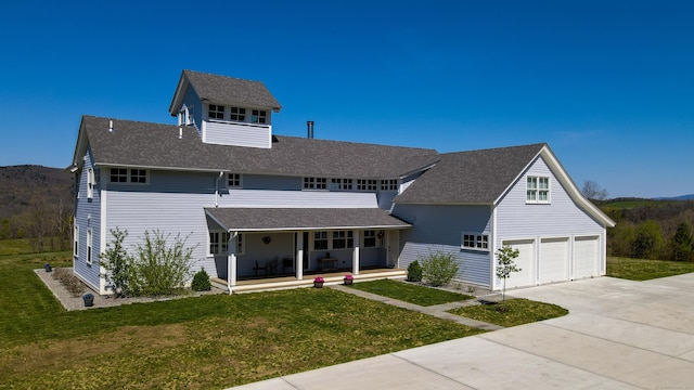 view of front of property with covered porch, an attached garage, concrete driveway, and a front lawn
