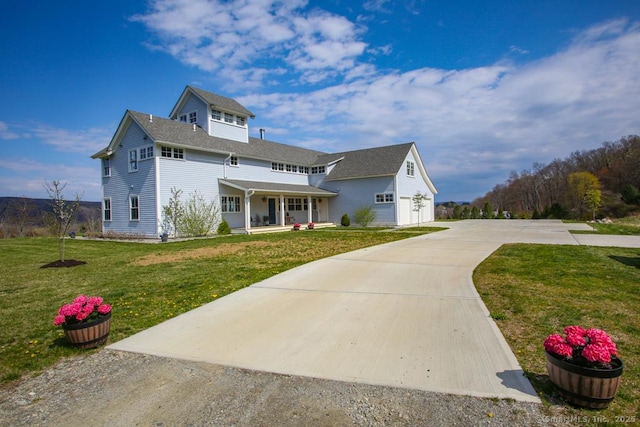view of front facade with a porch, concrete driveway, and a front yard