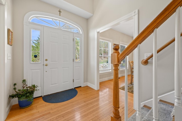 entrance foyer with light wood-style floors, baseboards, and stairs