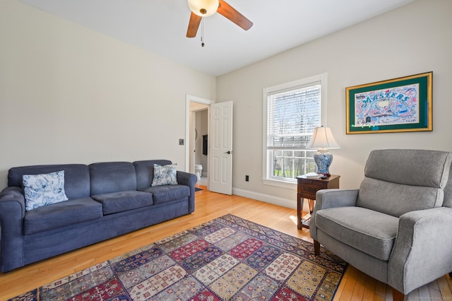 living room featuring baseboards, a ceiling fan, and wood finished floors