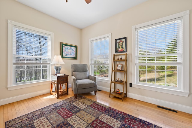 sitting room with baseboards, wood-type flooring, ceiling fan, and visible vents