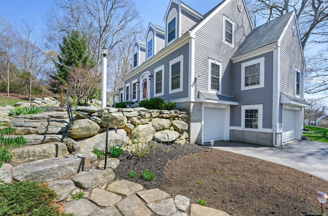 view of property exterior with an attached garage, roof with shingles, and driveway