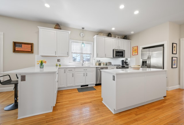 kitchen featuring a peninsula, appliances with stainless steel finishes, white cabinetry, and tasteful backsplash