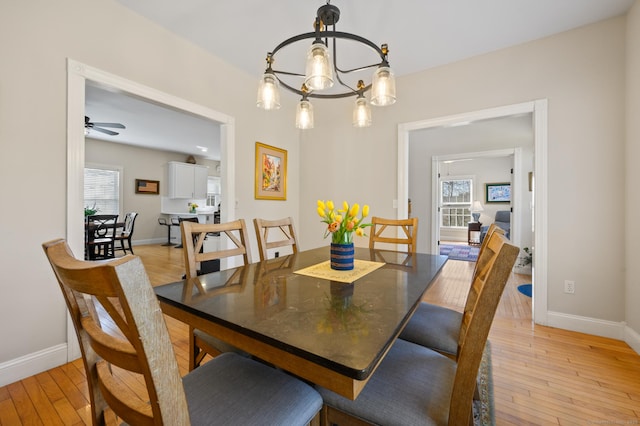 dining room featuring baseboards, light wood finished floors, and a wealth of natural light