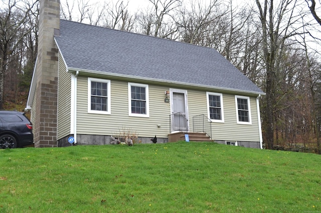 view of front of property with a chimney, a shingled roof, and a front lawn