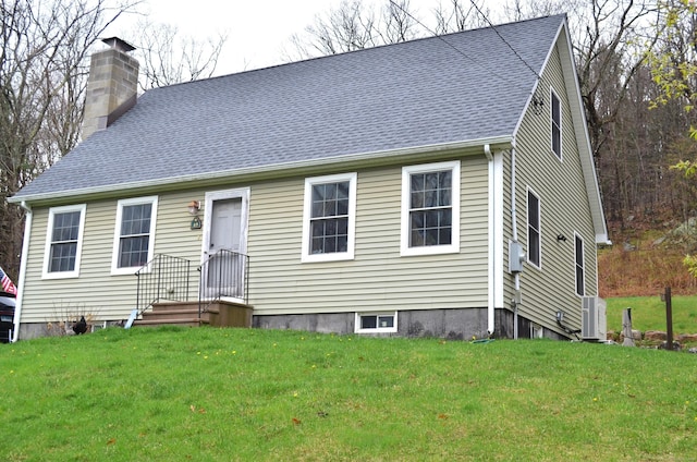 view of front of house featuring a chimney, a front yard, and roof with shingles