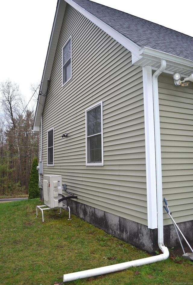 view of home's exterior featuring roof with shingles, a yard, and ac unit