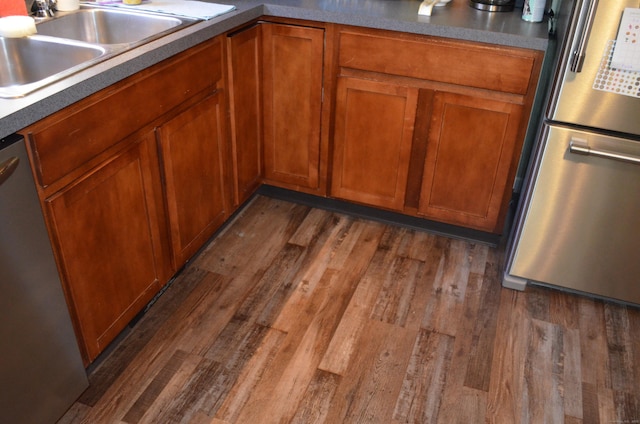 kitchen featuring stainless steel appliances, dark wood-style flooring, brown cabinets, and a sink