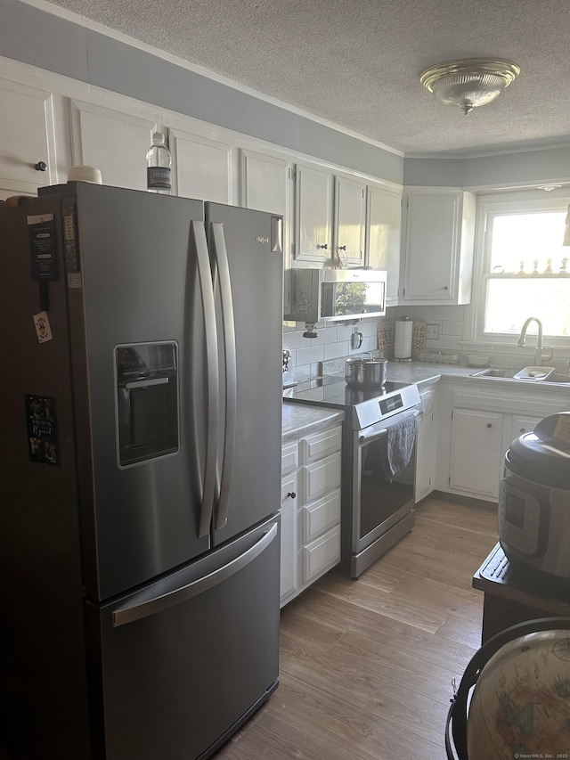 55 Virginia Ave Apt C, Groton, CT 06340 - kitchen featuring appliances with stainless steel finishes, a sink, a textured ceiling, white cabinetry, and backsplash