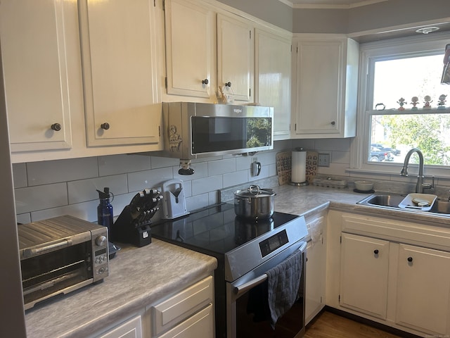 55 Virginia Ave Apt C, Groton, CT 06340 - kitchen with appliances with stainless steel finishes, light countertops, a sink, backsplash, and ornamental molding
