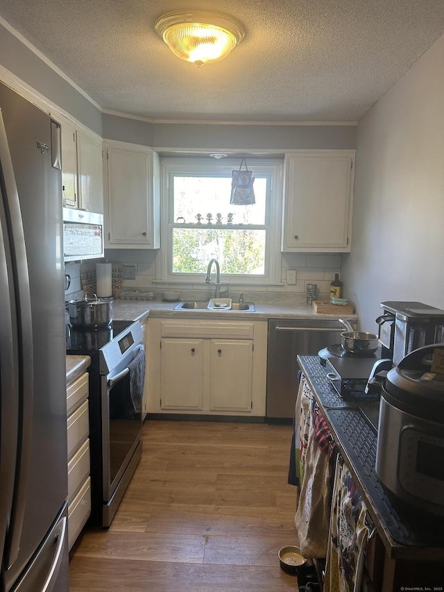 55 Virginia Ave Apt C, Groton, CT 06340 - kitchen with appliances with stainless steel finishes, a sink, wood finished floors, light countertops, and a textured ceiling