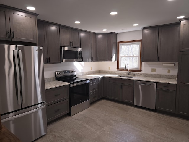 kitchen featuring dark brown cabinetry, appliances with stainless steel finishes, a sink, and light stone counters