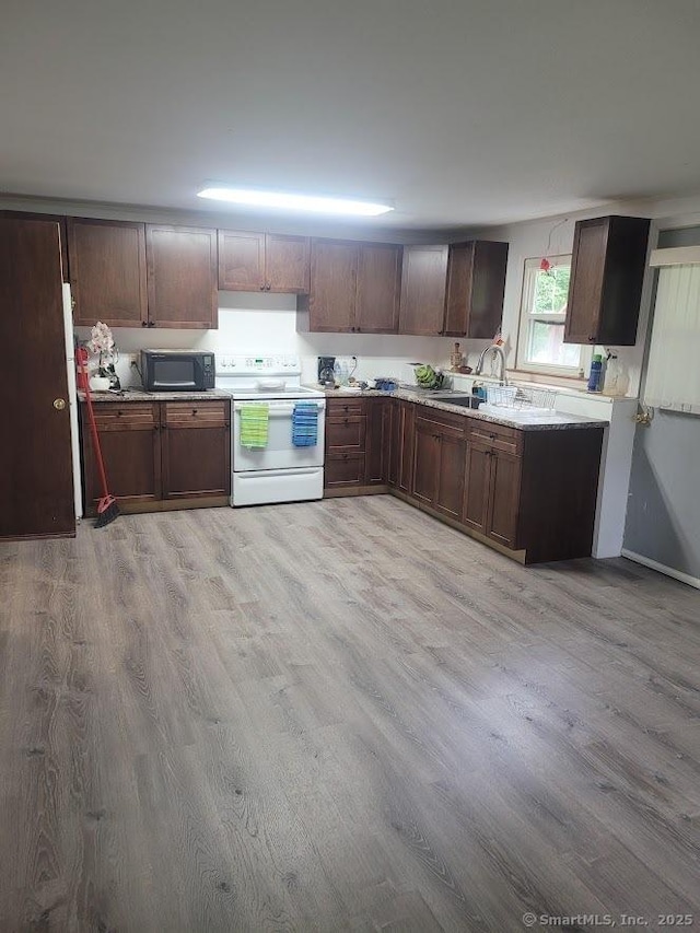 kitchen featuring light countertops, light wood-style flooring, white range with electric stovetop, and black microwave