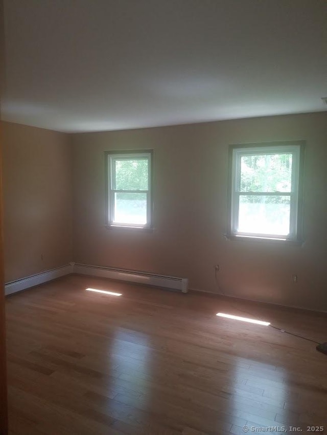 spare room with baseboards, a wealth of natural light, and wood finished floors