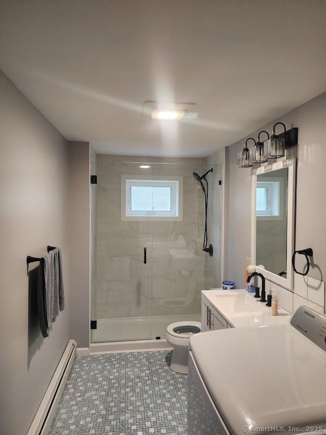 bathroom featuring washer / clothes dryer, a stall shower, vanity, a baseboard heating unit, and toilet