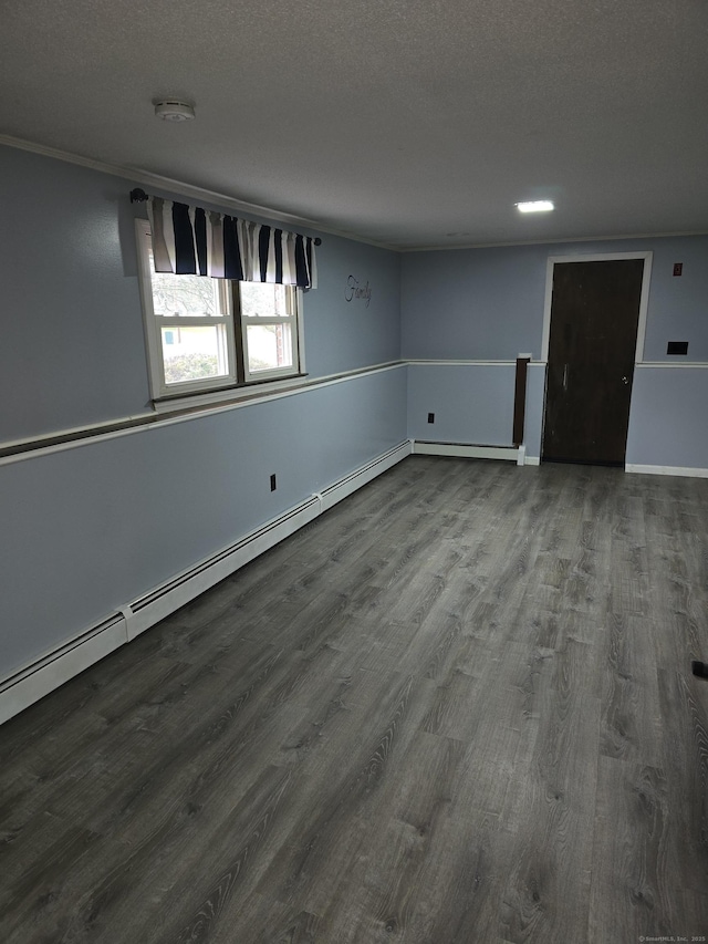 empty room with a textured ceiling, a baseboard radiator, and wood finished floors