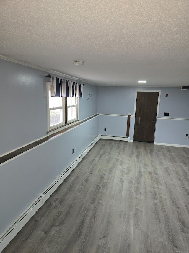 unfurnished room with a baseboard radiator, a textured ceiling, and wood finished floors