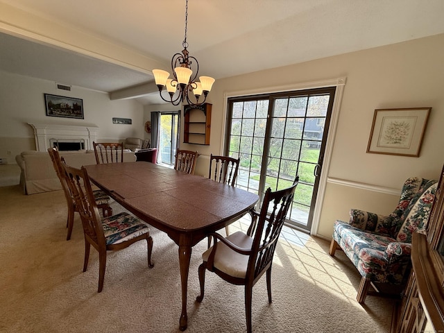 dining room with light colored carpet, a chandelier, and a fireplace