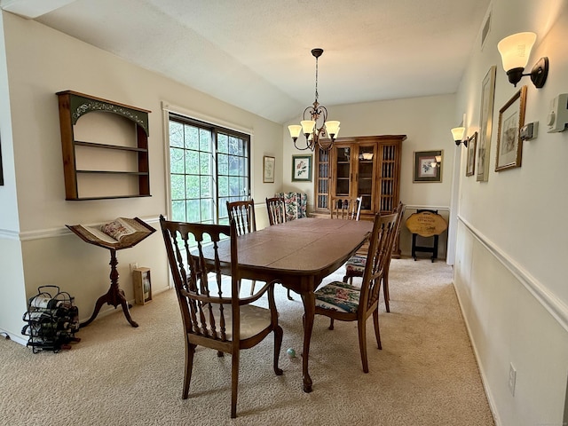 dining room with light carpet, a chandelier, and lofted ceiling