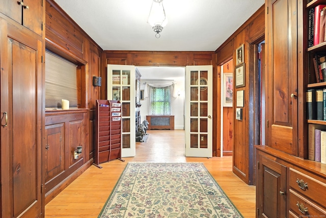 doorway to outside with light wood-style floors, wooden walls, and french doors