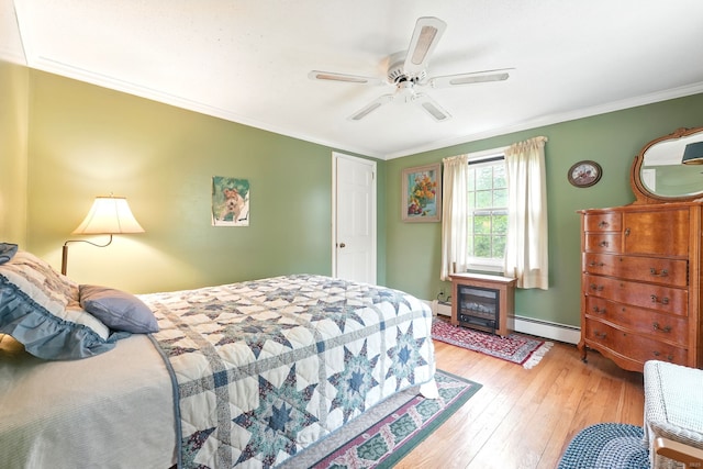 bedroom with a baseboard heating unit, light wood-style floors, crown molding, a fireplace, and a ceiling fan