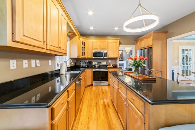kitchen featuring appliances with stainless steel finishes, a center island, a sink, light wood-style floors, and recessed lighting