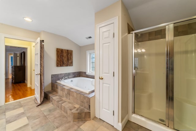 bathroom featuring a stall shower, lofted ceiling, a bath, and visible vents