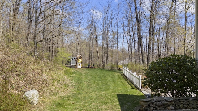 view of yard with a wooded view and fence