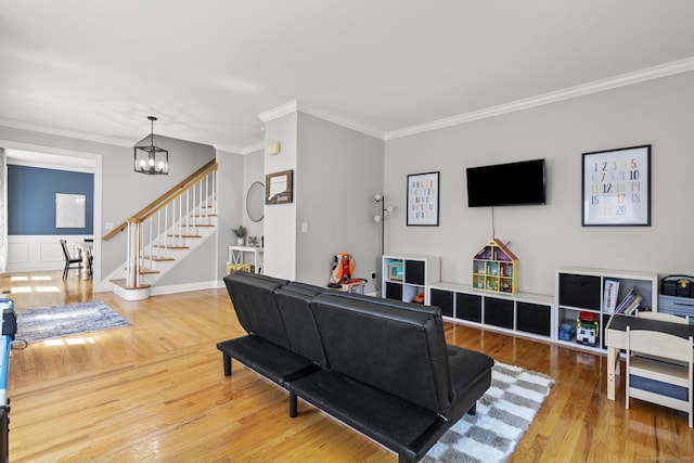 living room with crown molding, stairs, an inviting chandelier, and wood finished floors