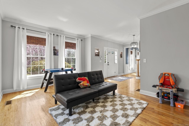 living area with an inviting chandelier, light wood-style floors, visible vents, baseboards, and ornamental molding