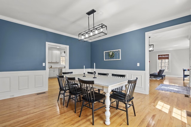 dining space with visible vents, wainscoting, and crown molding