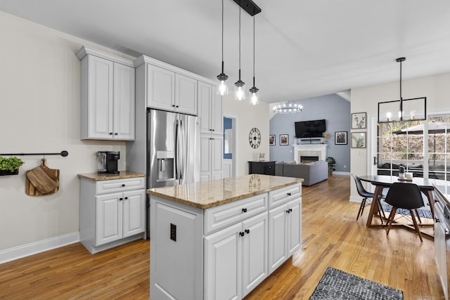 kitchen with a chandelier, decorative light fixtures, baseboards, light wood finished floors, and a fireplace