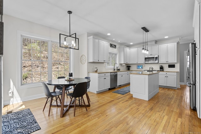 kitchen featuring an inviting chandelier, light wood-style flooring, stainless steel appliances, and baseboards