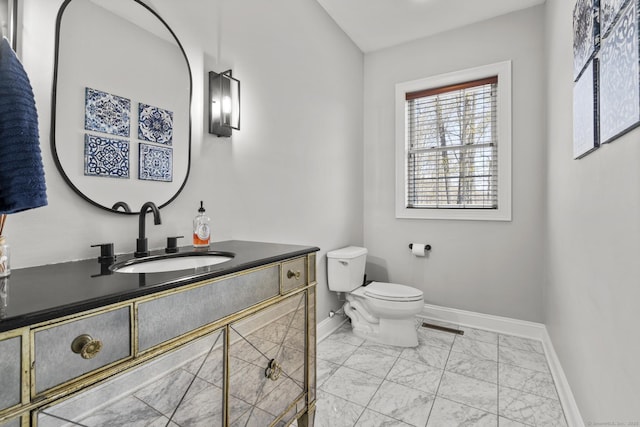 bathroom with baseboards, toilet, vanity, and marble finish floor