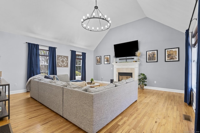 living room with light wood-type flooring, visible vents, a notable chandelier, and a fireplace