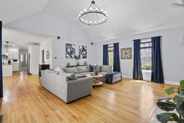 living room with light wood-style flooring, baseboards, high vaulted ceiling, and a notable chandelier