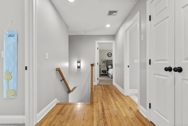 hall featuring recessed lighting, light wood-style floors, an upstairs landing, visible vents, and baseboards